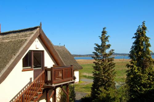 a house with a balcony and a tree at WG Bernstein - Reetdachhaus - Ruhe und Seeblick in Ostseebad Sellin
