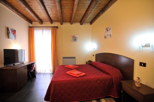 a bedroom with a bed with red sheets and a television at Hotel Piccolo in Termini Imerese