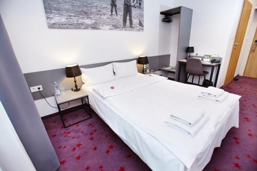 a hotel room with a large white bed and a desk at Koszary Arche Hotel in Góra Kalwaria