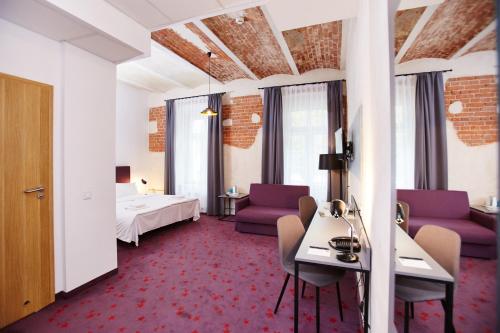 ein Hotelzimmer mit lila Stühlen und einem Bett in der Unterkunft Koszary Arche Hotel in Góra Kalwaria