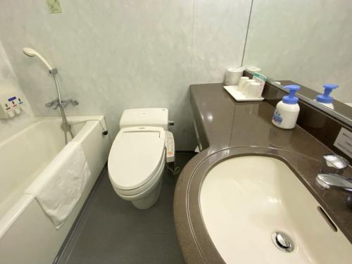 a bathroom with a toilet and a sink and a tub at Hotel 1-2-3 Kokura in Kitakyushu