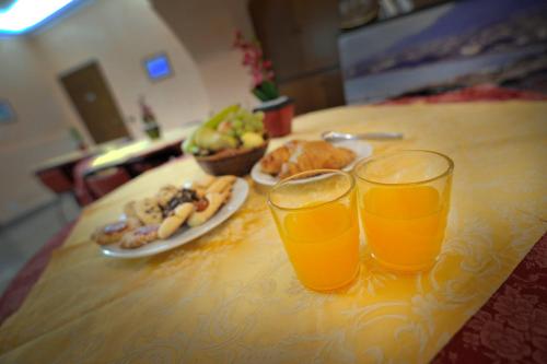 a table with two glasses of orange juice and a plate of food at Hotel Piccolo in Termini Imerese