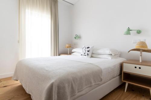 a white bedroom with a white bed and a window at Craveiral Farmhouse by Belong Staying & Feeling in São Teotónio
