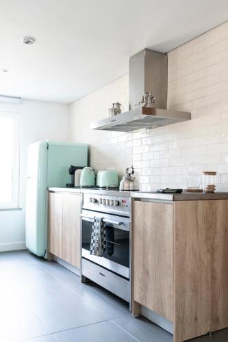 a kitchen with a stove and a refrigerator at Craveiral Farmhouse by Belong Staying & Feeling in São Teotónio