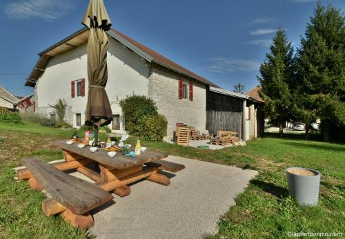 a picnic table in front of a building with an umbrella at Les Bouc'tins in Molain