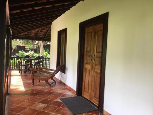 a porch with a wooden door and a bench at Montego Bay Beach Village - Morjim in Morjim