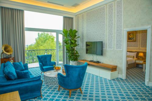 a living room with blue chairs and a television at Promenade Hotel Baku in Baku