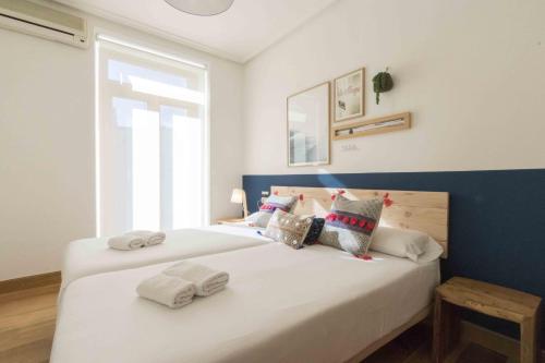 een slaapkamer met een bed met witte lakens en kussens bij The Rentals Collection - Easo in San Sebastian
