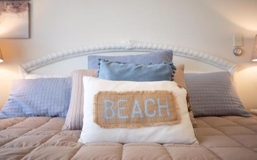 Bett mit Kissen mit dem Wort Strand drauf in der Unterkunft Beach Break Escape 226 in Mount Maunganui