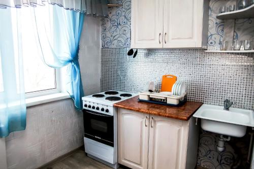 eine kleine Küche mit Herd und Spüle in der Unterkunft Апартаменты Зварыгина, 16 in Rakitnyy