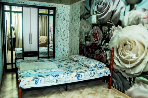 Bett in einem Zimmer mit einer Wand mit Rosen in der Unterkunft Апартаменты Зварыгина, 16 in Rakitnyy