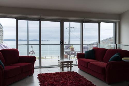 a living room with red couches and a view of the ocean at Casey's Beach Retreat in Batehaven