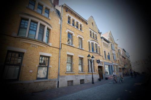 a large brick building on a street with people on a bike at Lichtrijke loft bij restaurant Den Olifant in Ieper