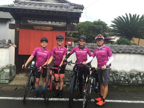 four men in purple shirts standing with their bikes at Guest House Mitsuka in Shishikui