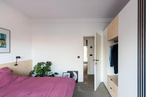 ein Schlafzimmer mit weißen Wänden und einem lila Bett in der Unterkunft Wolken en Zout in Bredene