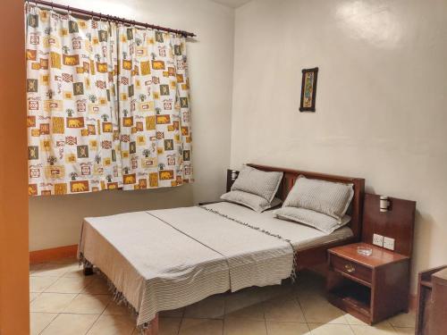 a bedroom with a bed and a curtain and a bed sidx sidx sidx at Marigold Guest House in Mombasa