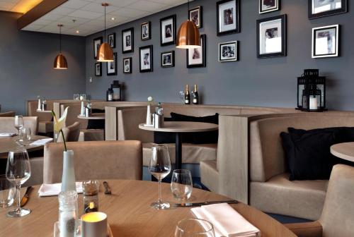 a restaurant with tables and chairs and pictures on the wall at Fletcher Hotel-Restaurant Wings-Rotterdam in Rotterdam