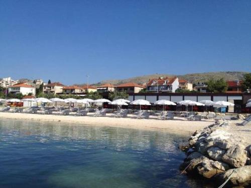 a beach with tables and chairs and umbrellas at SUNNY SIDE in Trogir