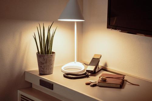 a table with a lamp and a phone on it at Hotel It Osaka Shinmachi in Osaka