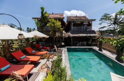 ośrodek z basenem, krzesłami i budynkiem w obiekcie Royal JJ Ubud Resort & Spa w mieście Ubud