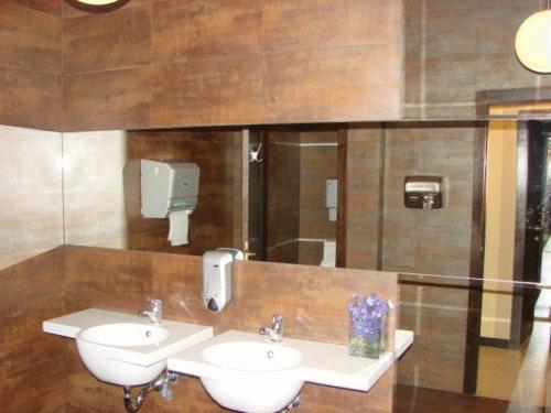 a bathroom with two sinks and a dispenser on the wall at Griff Hotel Zalau in Zalău