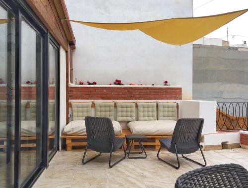 a patio with chairs and a couch on a building at Hostel Numero Trece in Alicante