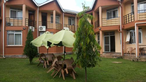 a group of tables and umbrellas in front of a building at Westcliff Hotel in Lira