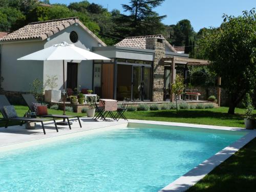- une piscine avec un parasol et une maison dans l'établissement Maison Pigeonnier, à Alet-les-Bains
