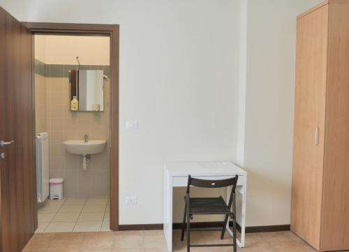 a bathroom with a white table and a chair at Ostello Cuneo in Cuneo