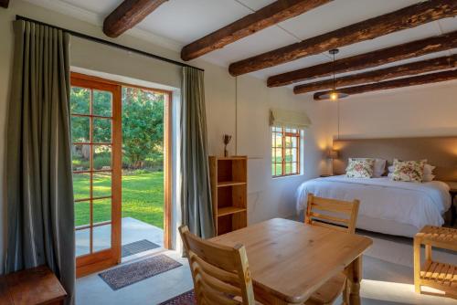 Schlafzimmer mit einem Bett, einem Tisch und einem Fenster in der Unterkunft Honeyrock Cottages in Kleinmond