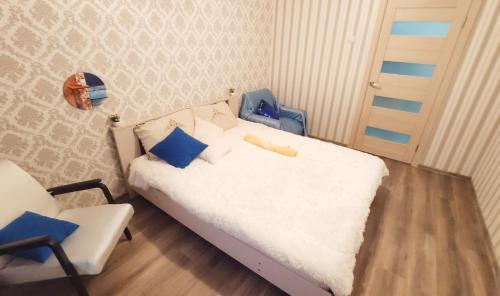 a small bedroom with a white bed and a chair at Good Apartments in Gomel