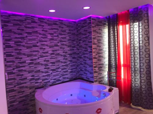 een badkamer met een bad in een kamer met een bakstenen muur bij Loft romántico in Algeciras