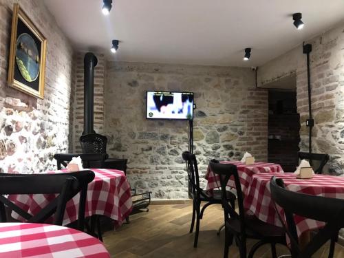 un restaurante con 2 mesas y TV en la pared en Old Bazaar Rooms, en Korçë