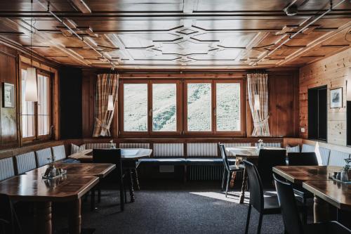 a dining room with tables and chairs and windows at Hotel Adler in Warth am Arlberg