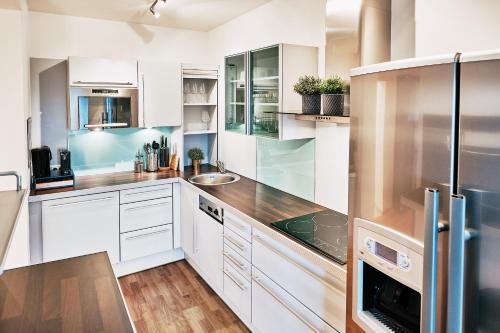 uma cozinha com armários brancos e electrodomésticos de aço inoxidável em Kaiser Apartments - City Centre of Graz em Graz