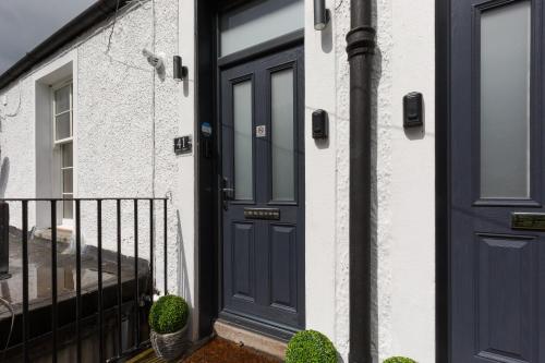 a blue door on a house with a balcony at Dollar Apartments-41 Bridge Street in Dollar