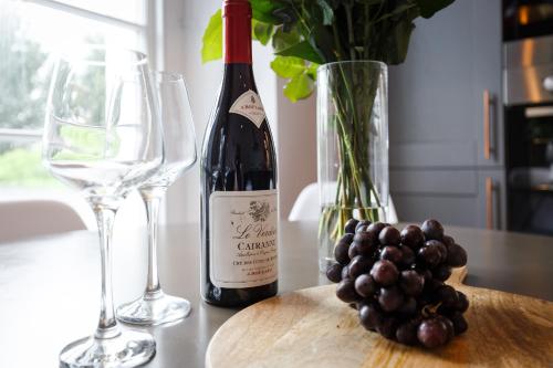 a bottle of wine and a glass and a bunch of grapes at Dollar Apartments-41 Bridge Street in Dollar
