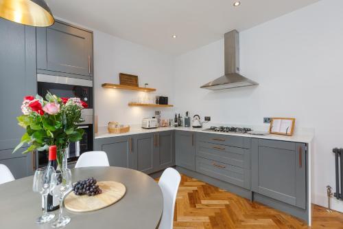 a kitchen with gray cabinets and a table with flowers at Dollar Apartments-41 Bridge Street in Dollar