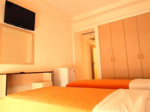 a room with two beds and a tv on the wall at Hotel Victoria in Kilkís