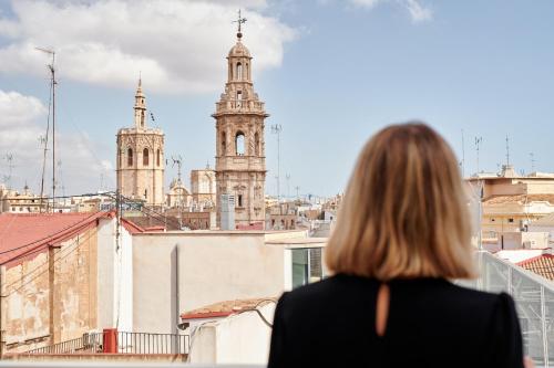 a woman looking out at the city from a building at Room Mate Cosmo - City Centre, Valencia in Valencia