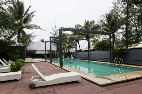 a swimming pool with two white lounge chairs next to it at Marbela Beach Resort in Morjim