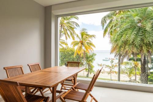 a dining room with a table and chairs and a large window at CAPLAGE -Beach Front Luxury Apartment at Searock in Tamarin