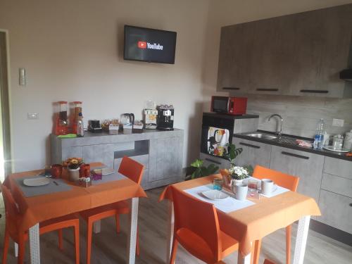 a kitchen with two tables and orange chairs in a room at R&B mediterraneo in Bosa
