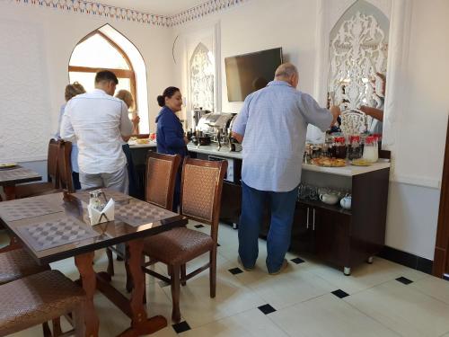 a group of people standing at a bar in a restaurant at An-Nur boutique in Bukhara