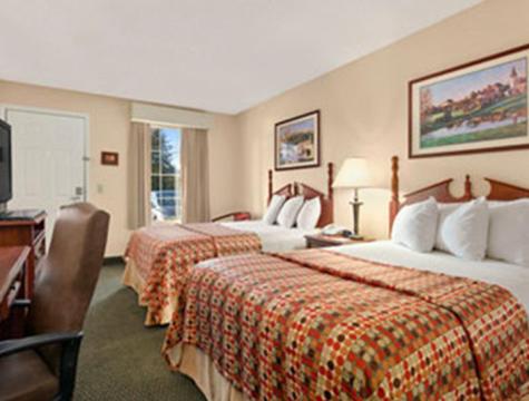 a hotel room with two beds and a television at Baymont by Wyndham Grenada in Grenada
