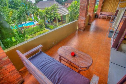 a balcony with a table and a couch and a red ball at Pondok Kutuh Guest House in Ubud