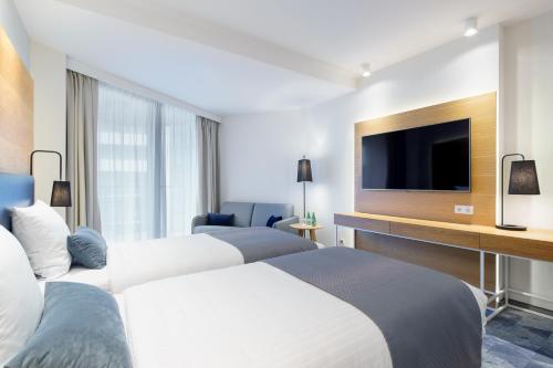 two beds in a hotel room with a flat screen tv at Seaside Park Hotel in Kołobrzeg