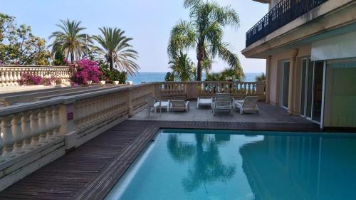 - une piscine à côté d'une maison avec vue sur l'océan dans l'établissement Le Victoria, 2p moderne, les pieds dans l'eau, Parking, Piscine, à Menton