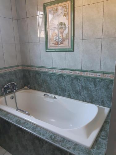 a bath tub in a bathroom with a picture on the wall at Angela's Place in Durban