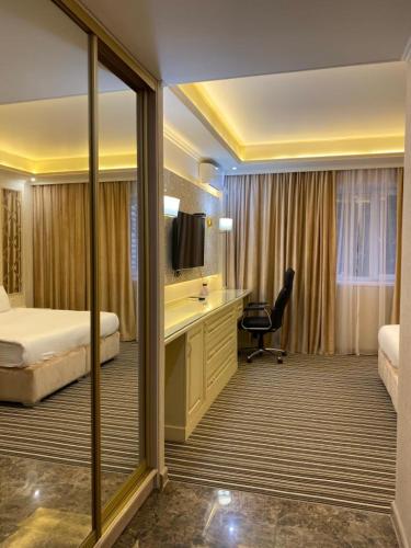 a hotel room with a bedroom with a bed and a desk at Barhat Hotel & SPA in Taraz